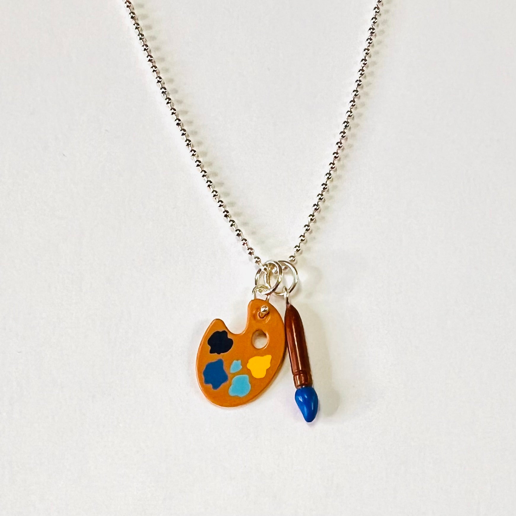 Lego palette and paint brush toy charms hanging of a sterling silver chain. Palette has light blue, dark blue , yellow and black paint like palette Vincent would have used for his Starry Night Master piece painting