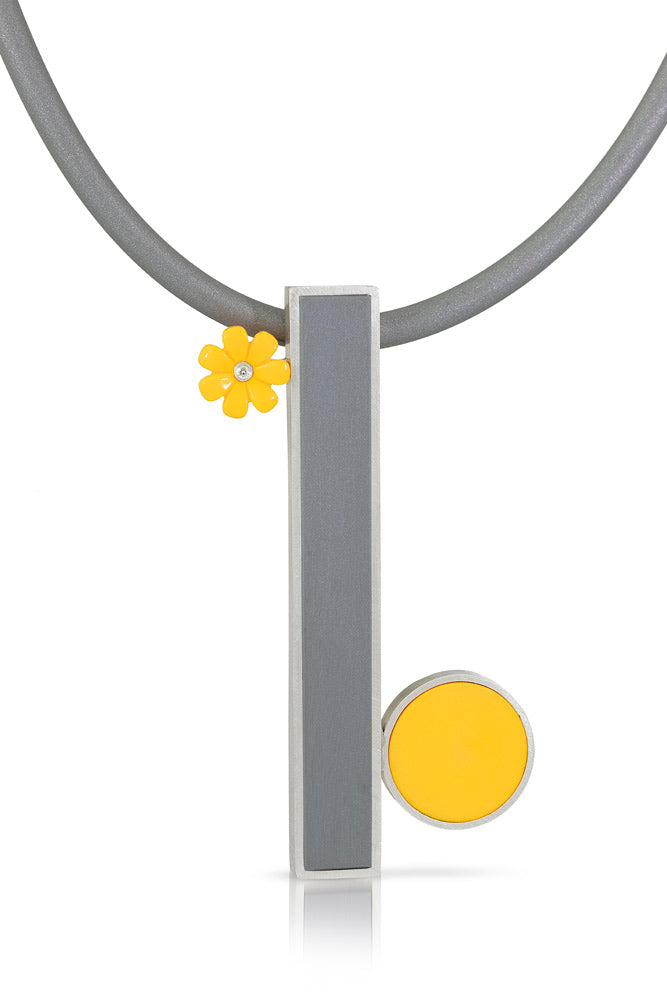 a long grey lego tile laying vertically off a grey rubber cord. On the top left corner there is a yellow lego flower with a diamond in the center. On the bottom right is a yellow round lego tile juxtaposed