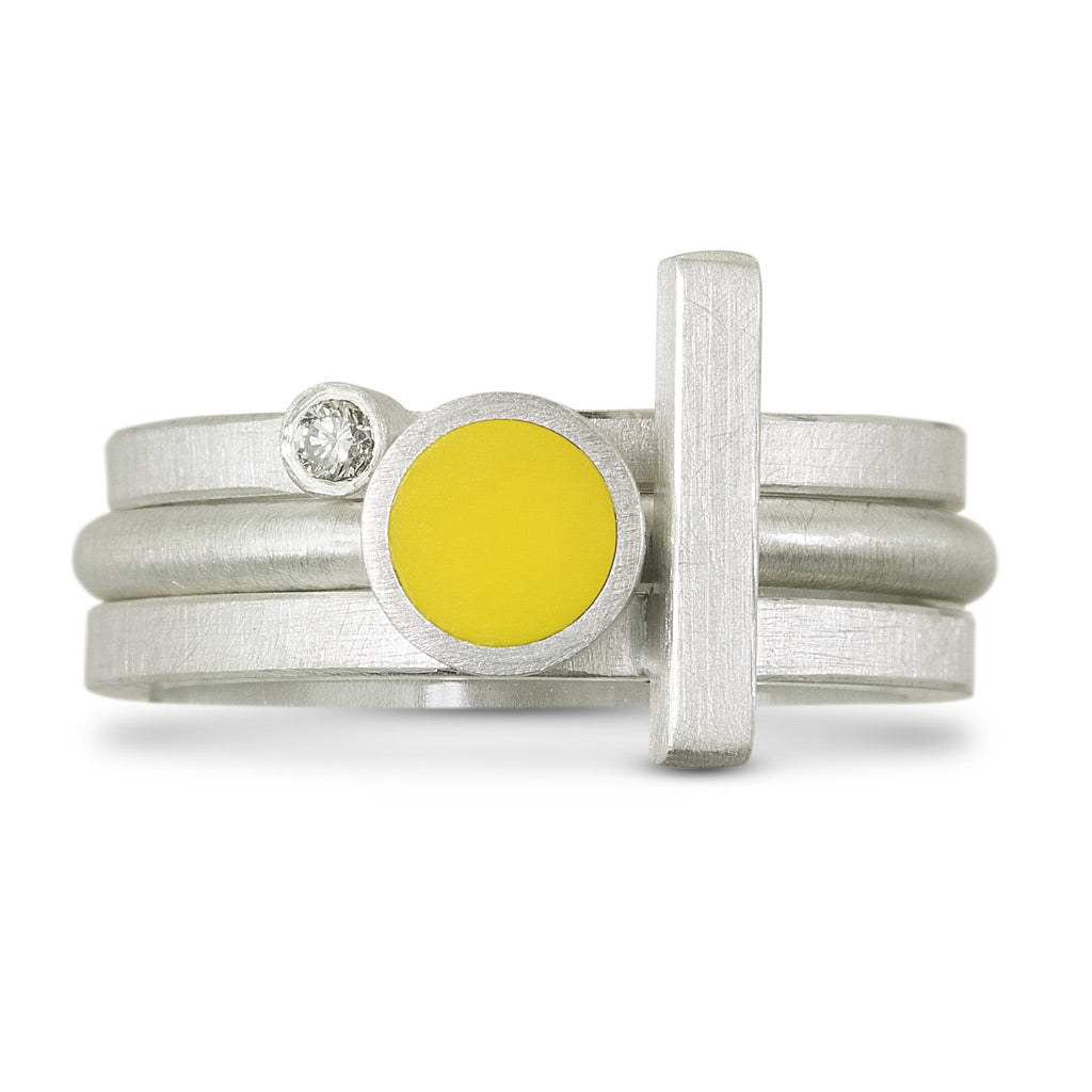 3 sterling silver rings pictures stacked together. One ring is a diamond ring,  one has a yellow LEGO dot in the center, the last one is a silver bar that goes across the other two