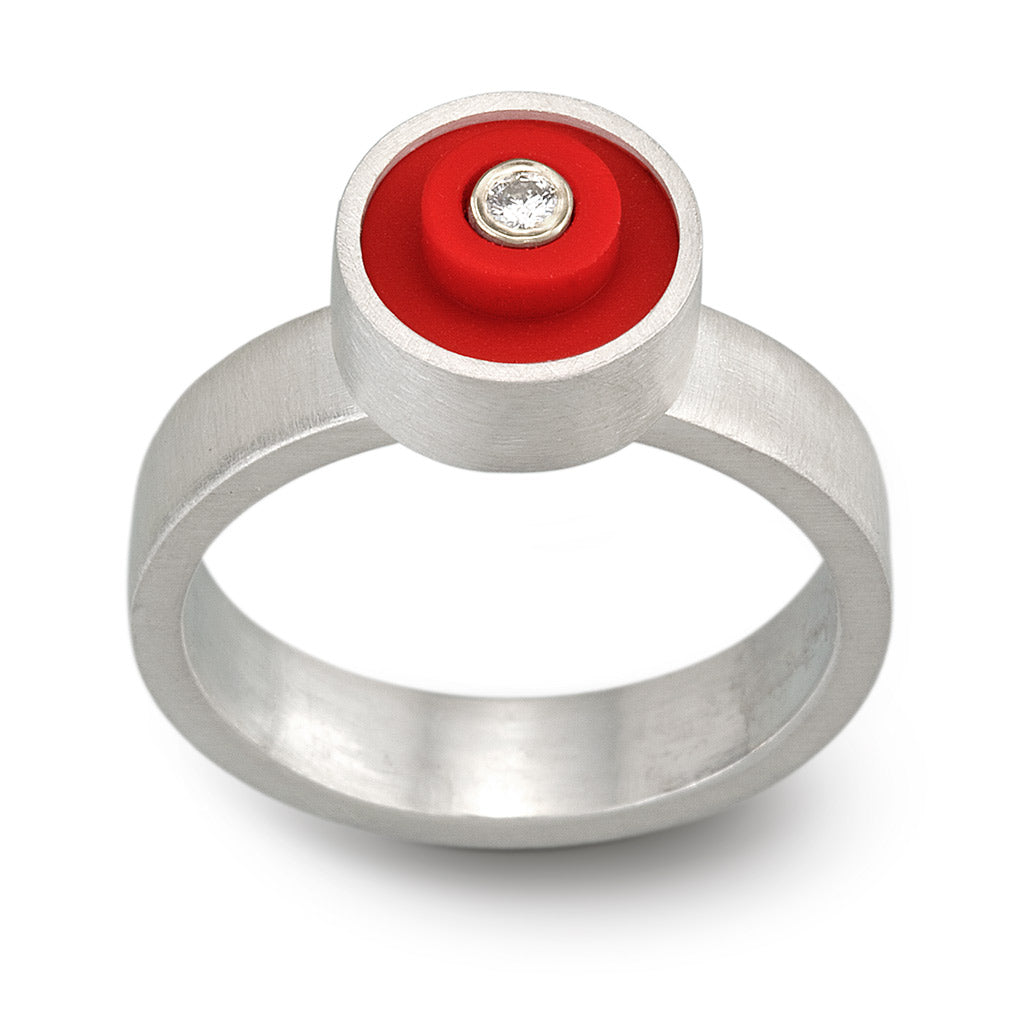 Red LEGO ring with a LEGO stud on top, set in sterling silver with a diamond in the middle on a band with a brushed finish