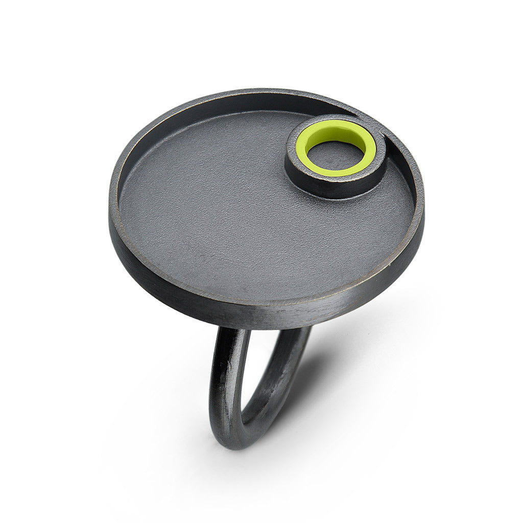 a sterling silver oxidized ring with a circle design on top with a lime green lego piece made into a tube on the top  surrounded by silver