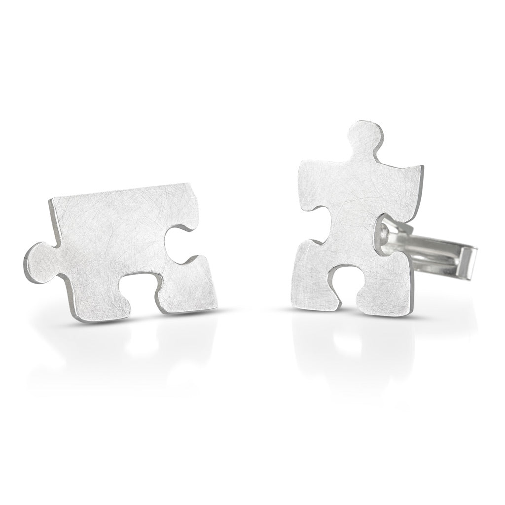 cuff links in the shape of puzzle pieces that fit together, but shown apart