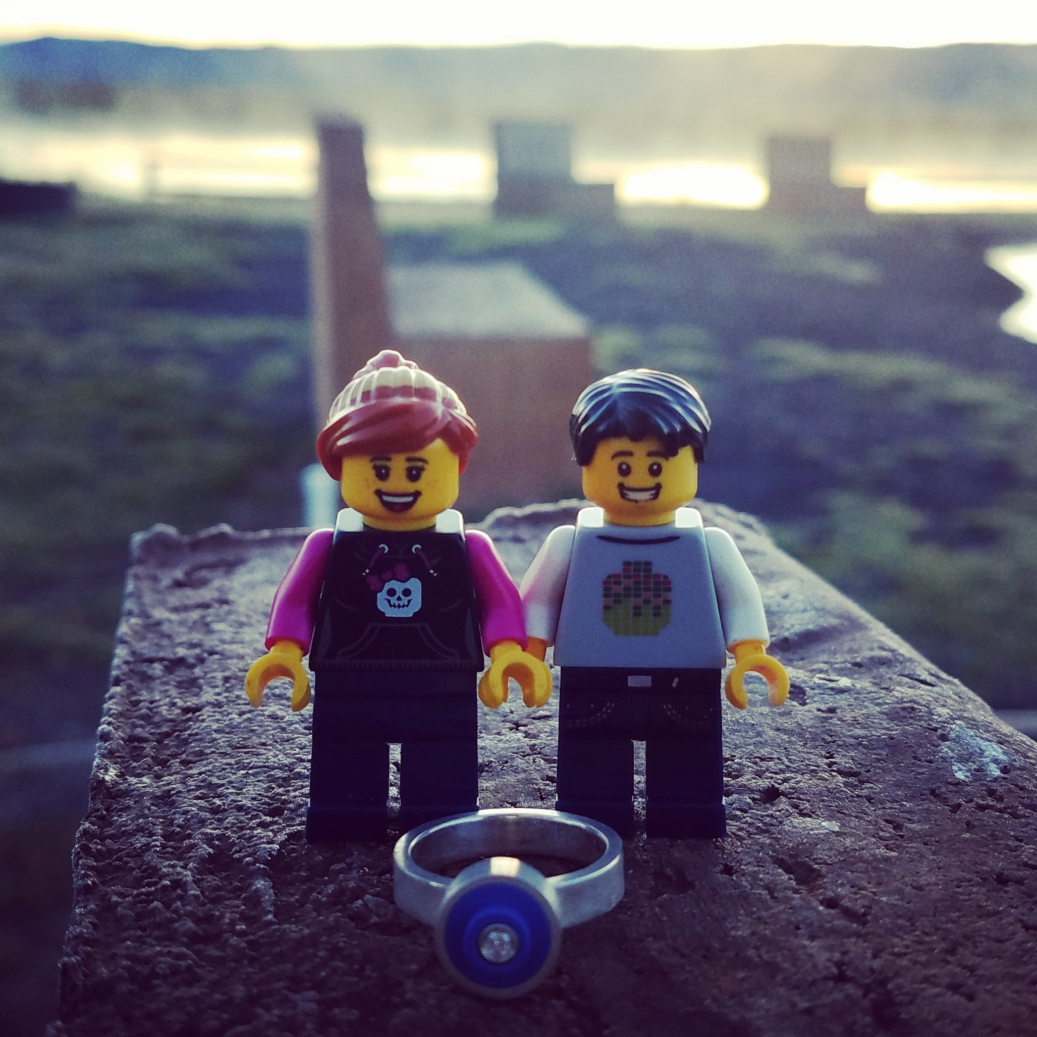 Two LEGO mini-figures standing in front of a lego and diamond ring