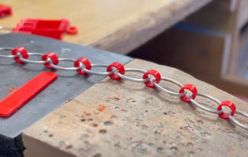 On the work bench is sterling silver links connected with red recycled lego bricks 