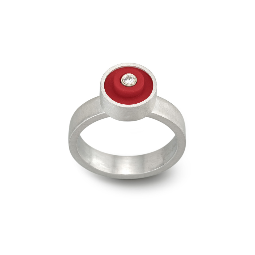 Red LEGO ring with a round LEGO stud on top, set in sterling silver with a diamond in the middle on a band with a brushed finish