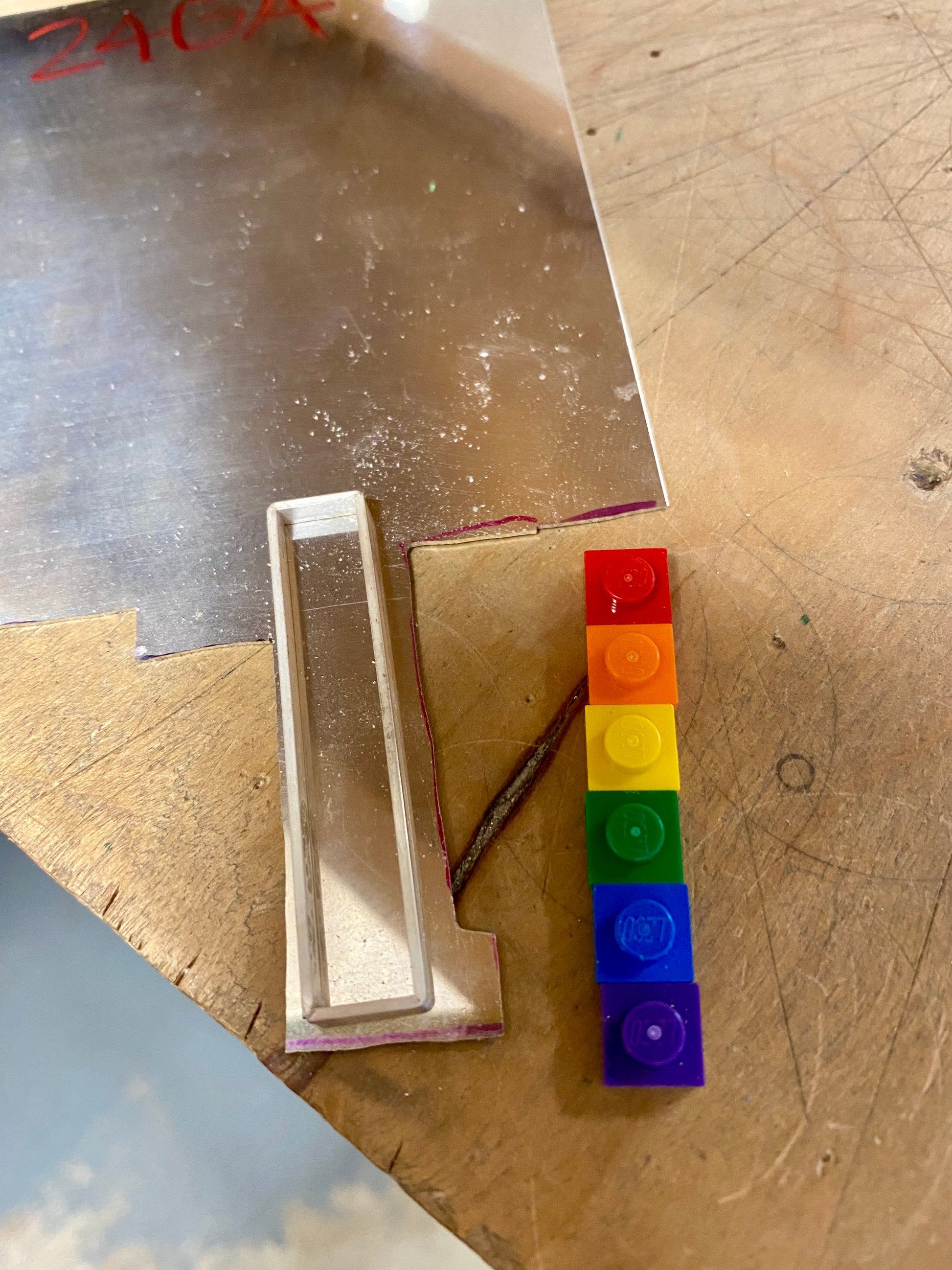 on the work bench showing the process of how the pendant is created with first shaping the bezel that will surround the lego pieces