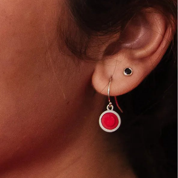 Silver earrings with red circular LEGO studs on a white background