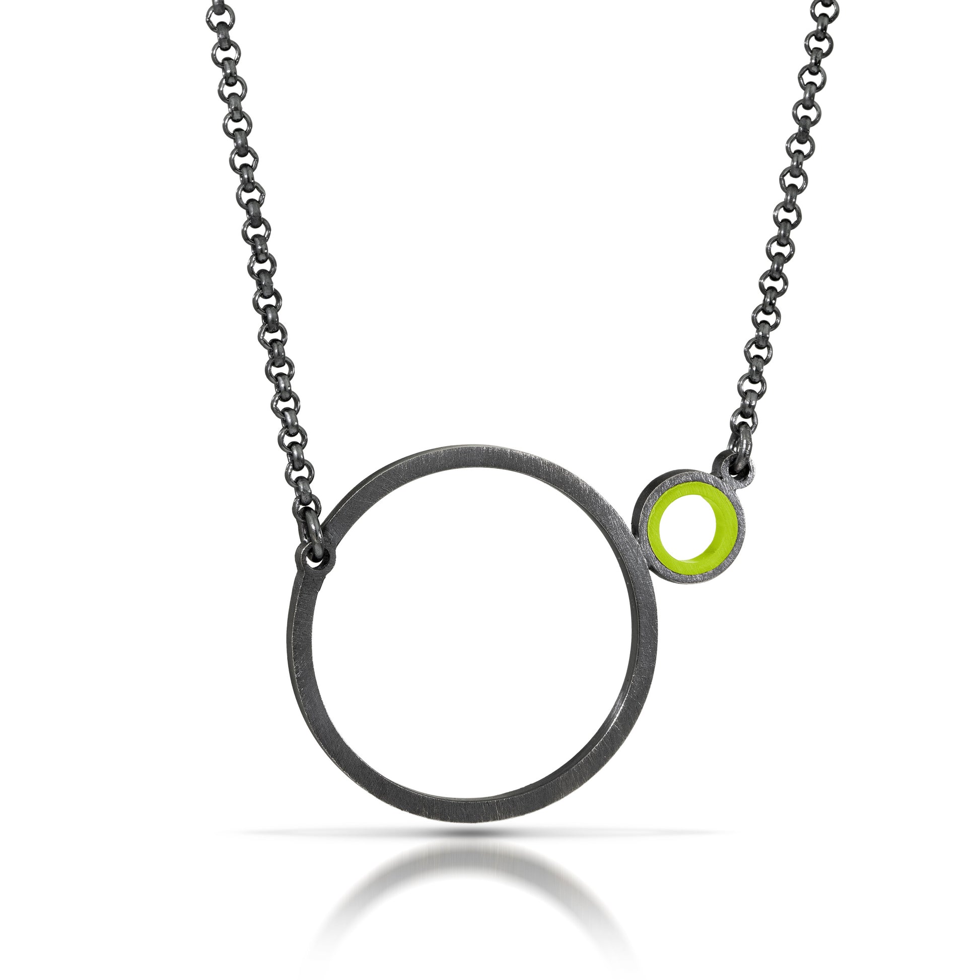 a necklace with a dark finish on the metal with a large circle pedant in center with a small circle attached to the side with a light green recycled piece of a lego tube inside the small circle