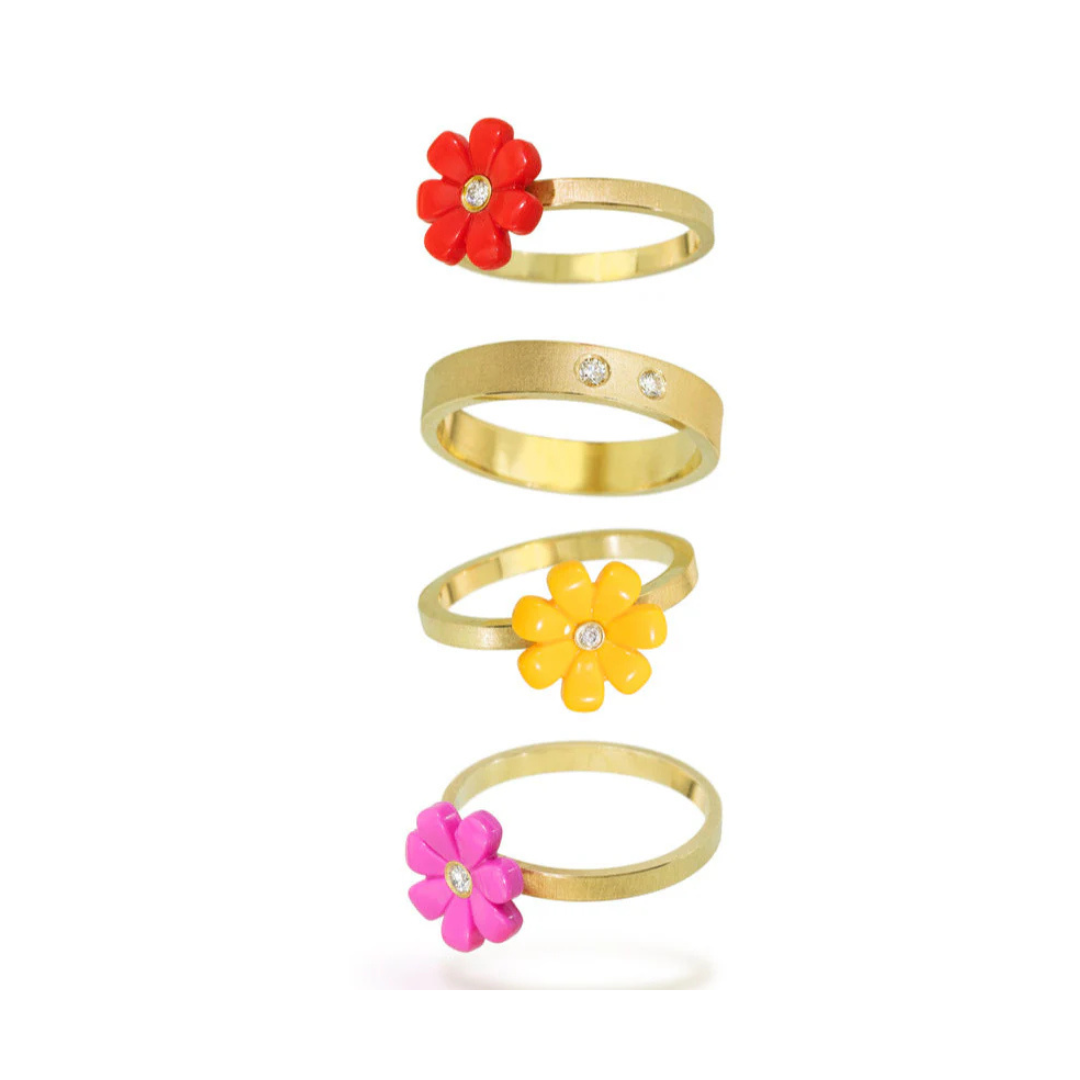 Gold ring with a yellow flower and small diamond leaning up against a gold band with 2 round diamonds on a white background 