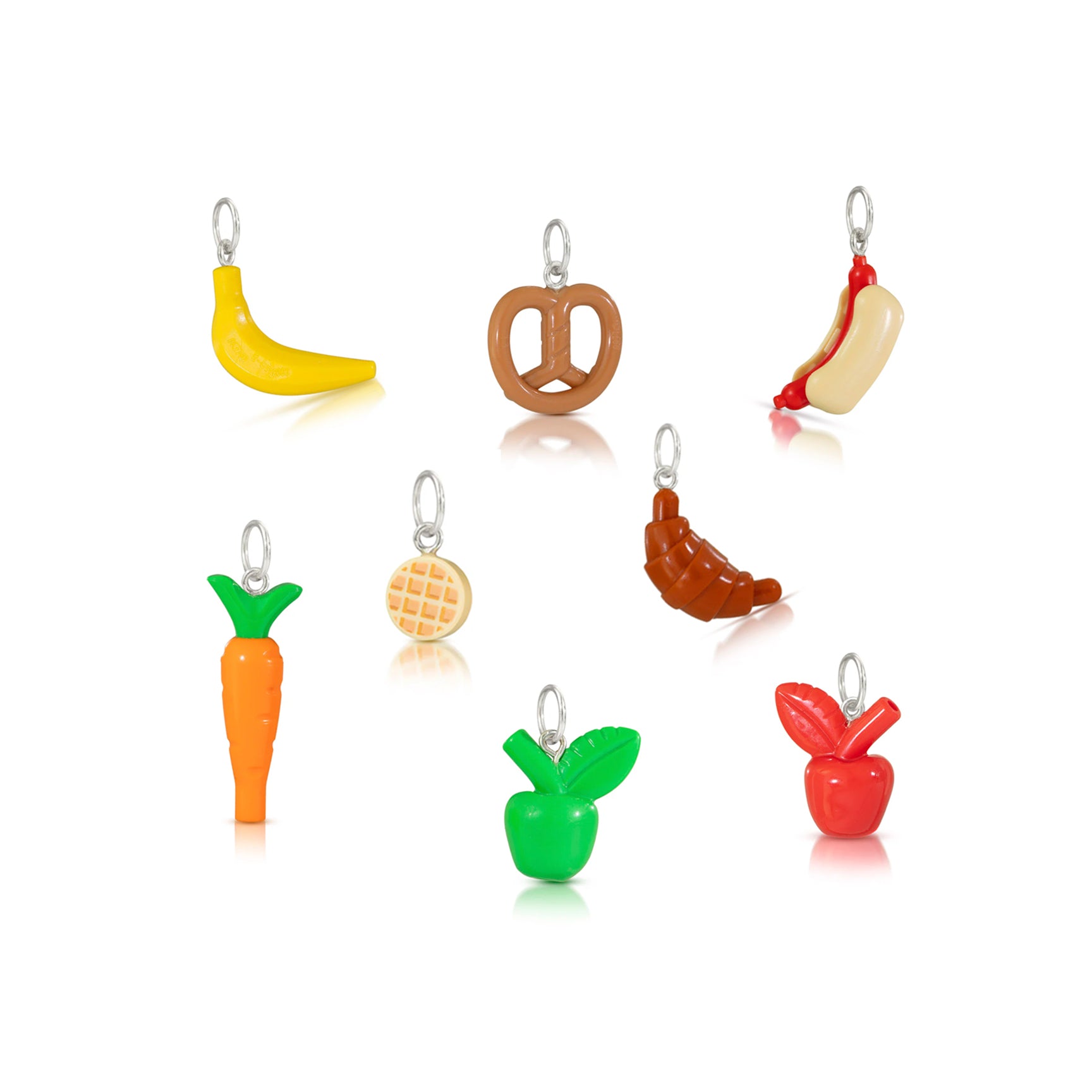 Group of charms all standing together- LEGO banana charm, LEGO pretzel charm. LEGO hot dog charm, LEGO carrot charm, LEGO waffle charm, LEGO croissant charm, LEGO green juicy apple charm, and La EGO red juicy apple charm