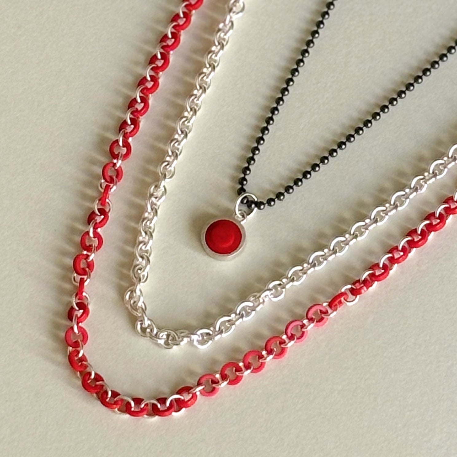 3 chains shown laying down , how they would look worn on the neck in different lengths for a stylist layered look.