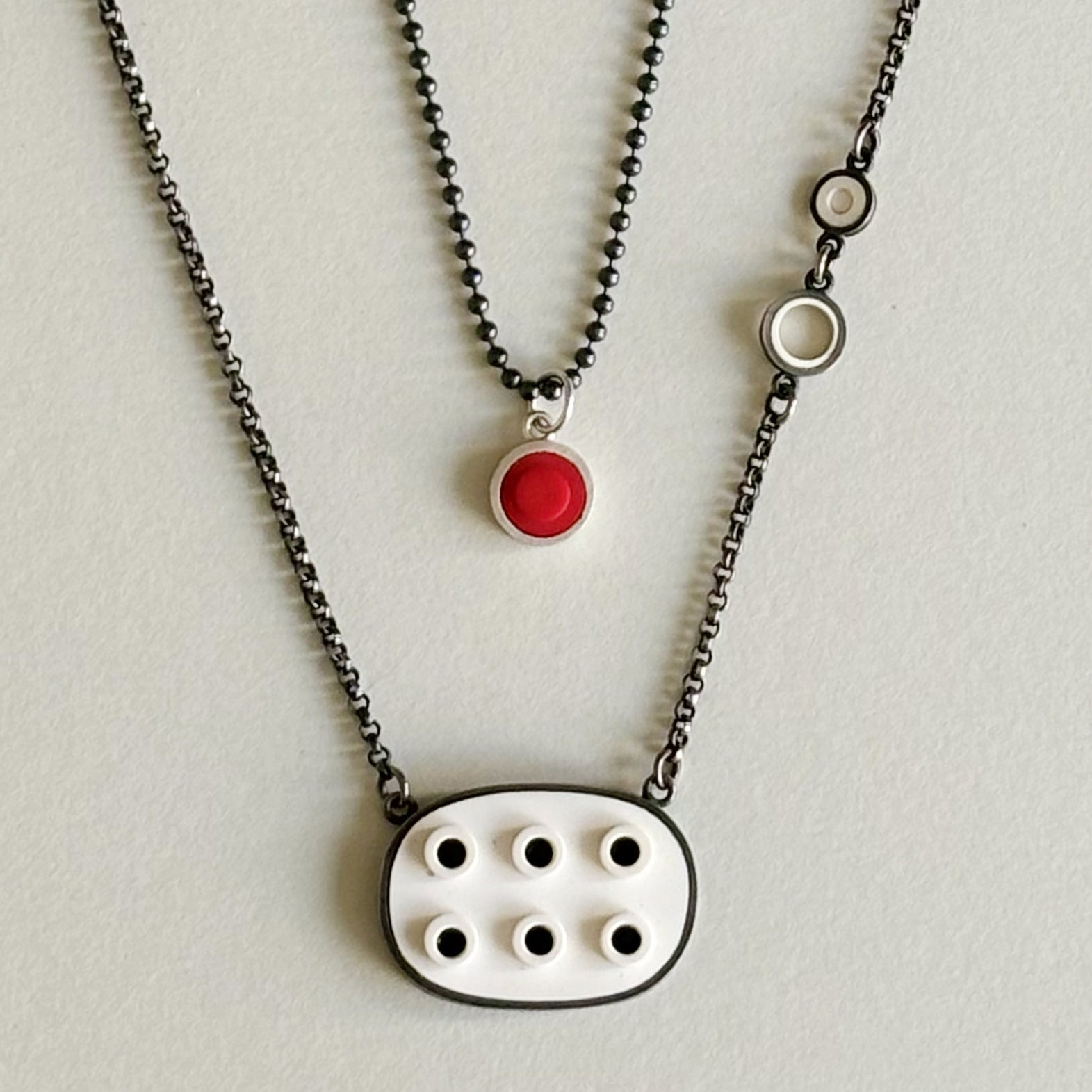 Two necklaces shown with the oxidized  bead chain to show how nicely it layers and styles with other chains at different lengths. One is a red lego dot charm and one a white lego oval necklace