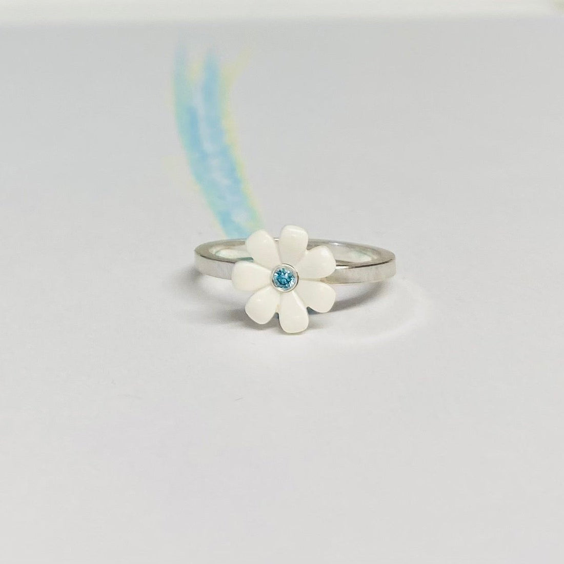 Sterling silver ring with a white LEGO friends daisy on top with a blue diamond set into the middle