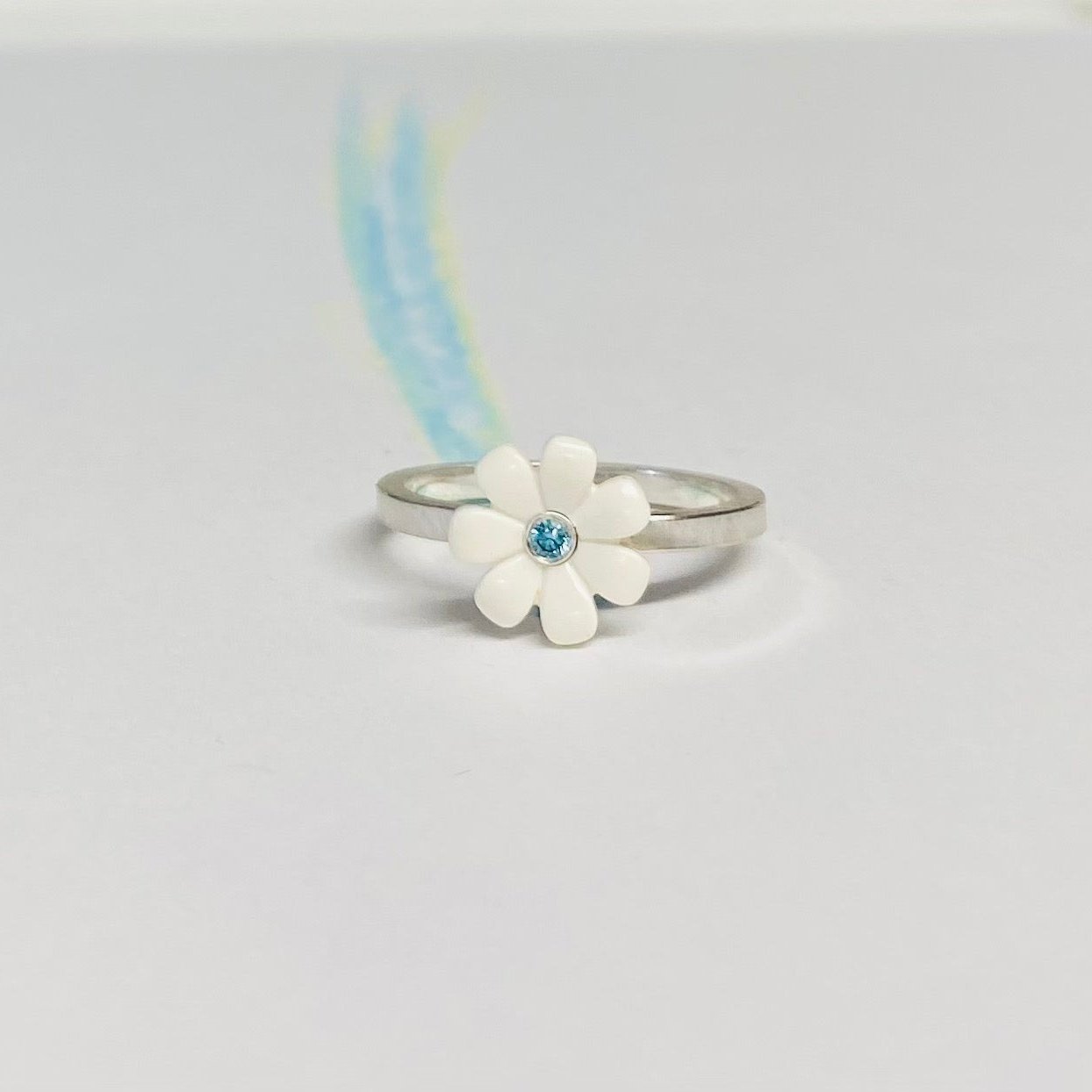 Sterling silver ring with a white LEGO friends daisy on top with a blue diamond set into the middle