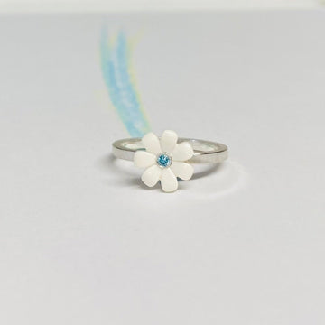 Sterling silver ring with a white LEGO friends daisy on top with a blue diamond set into the middle