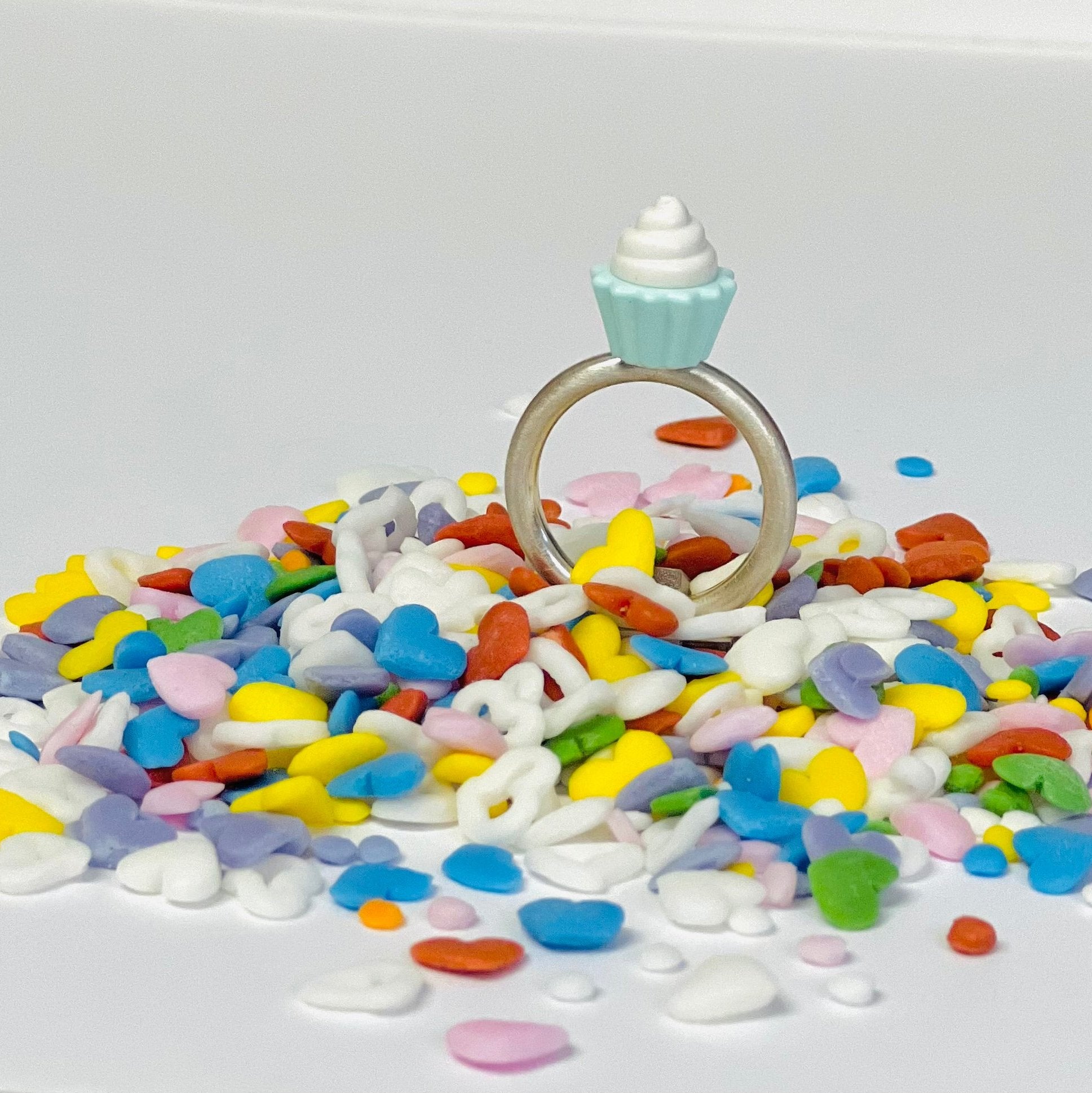  Sterling silver ring with LEG0 mini-figure vanilla cupcake accessory toy on top of ring displayed on colorful heart shaped sprinkles 