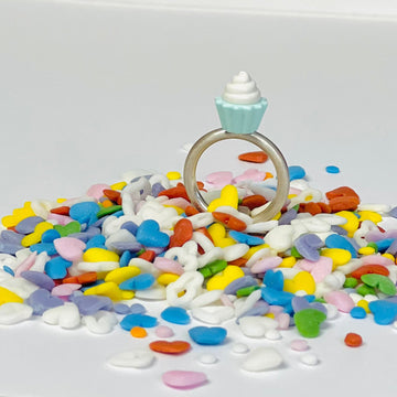  Sterling silver ring with LEG0 mini-figure vanilla cupcake accessory toy on top of ring displayed on colorful heart shaped sprinkles 