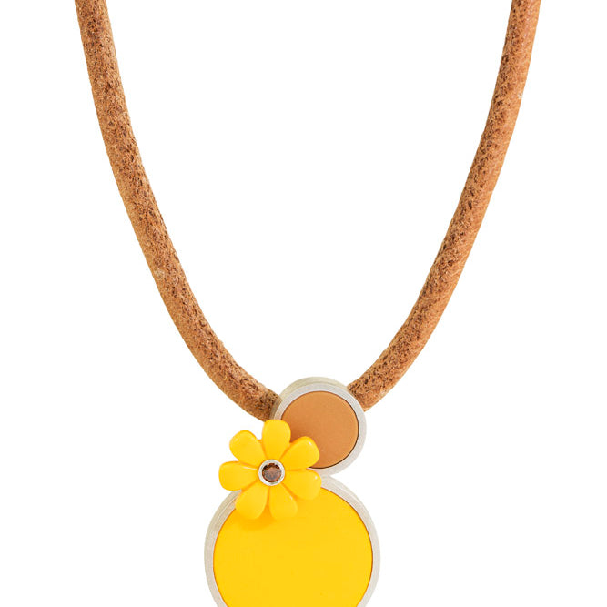 a pendant that has. 2 lego dots one small light brown, one large yellow with a yellow lego daisy juxtaposed with a brown diamond in center on a leather cord 