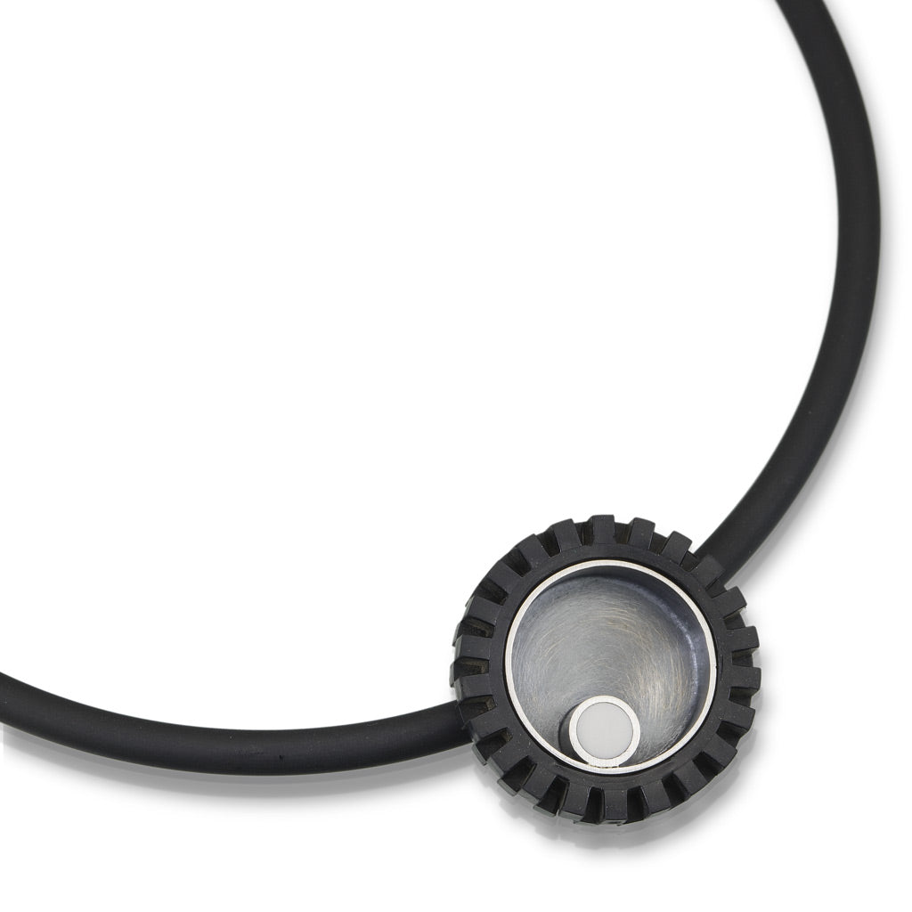 LEGO tire pendant with accents of silver and a white LEGO piece to create modern art jewelry